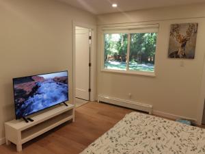 uma sala de estar com uma televisão de ecrã plano num stand ao lado de uma janela em Garden Home em Surrey