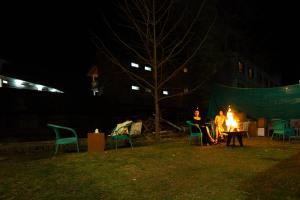 a group of people sitting around a fire at night at Hotel Rising Star in Manāli