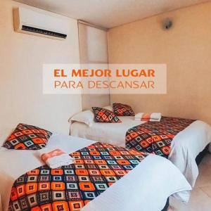 two beds in a room with a sign that says el metro ligerzonazona at Hotel Tierra Santa in Santa Fe de Antioquia