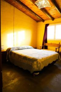 ein Schlafzimmer mit einem Bett in einem gelben Zimmer in der Unterkunft Colonia Indalo casa de campo in San Carlos