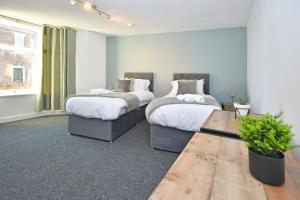 a bedroom with two beds and a table in it at Lyndale House - By Sigma Stays in Crewe
