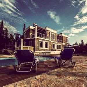 a house with two chairs in front of a swimming pool at Villa Vera in Agios Nikitas