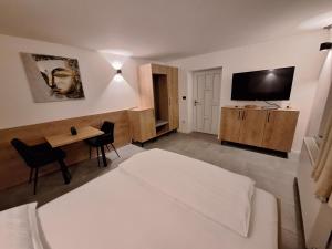 Habitación de hotel con cama, escritorio y TV. en Prenočišča Kralj, en Komenda