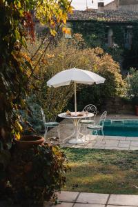 una mesa con sillas y una sombrilla junto a la piscina en Casa Soleil Casa principal y Pajar 11 personas, en Vilopríu