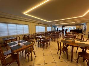 a restaurant with wooden tables and chairs and windows at Hotel Vila do Farol in Bombinhas