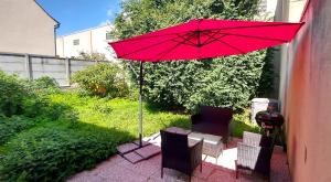 a red umbrella sitting on a patio with two chairs at Silver&Gold House Pro & Family in Ivry-sur-Seine