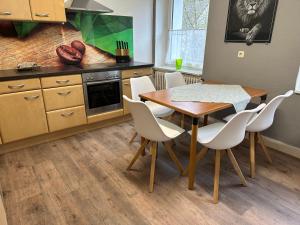 a kitchen with a wooden table and white chairs at An der Linde in Kall