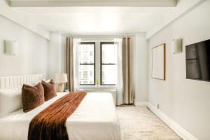 a white bedroom with a large bed and a window at 73-1004 New Studio UWS Doorman Gym in New York