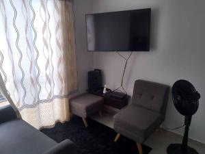 a living room with a chair and a flat screen tv at Apartamento Amoblado Alameda del Rio Barranquilla in Barranquilla
