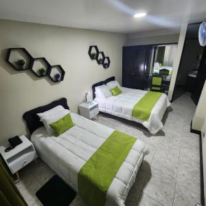 a hotel room with two beds with green sheets at Hotel América Heredia in Heredia