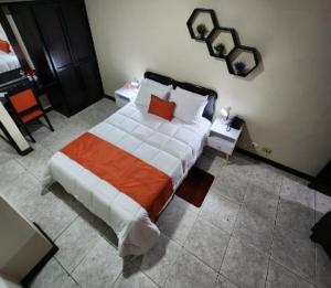 1 dormitorio con 1 cama con manta naranja y blanca en Hotel América Heredia, en Heredia