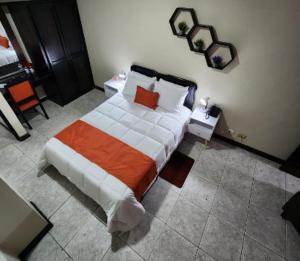 a bedroom with a bed with an orange and white blanket at Hotel América Heredia in Heredia