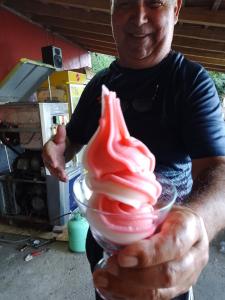 un hombre sosteniendo un tazón de helado rojo en Apartman i Krčma u Planini, en Bojnik