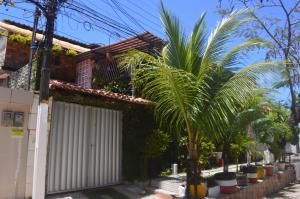 une maison avec une porte blanche et des palmiers dans l'établissement Pousada Olinda Delícia, à Olinda