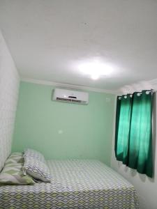 1 dormitorio con 1 cama y una ventana con cortinas verdes en Casa do breno, en Paraipaba