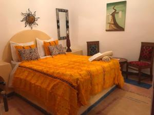 a bedroom with a bed with an orange comforter at Hôtel Riad Gnaoua in Essaouira