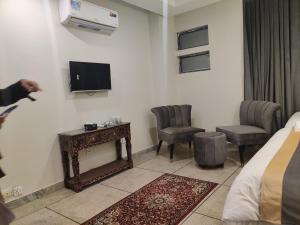 um quarto de hotel com uma cama e uma televisão e cadeiras em Hotel Swiss Pearl em Lahore