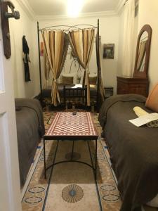 a room with two beds and a mirror and a table at H&ocirc;tel Riad Gnaoua in Essaouira