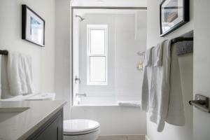 a white bathroom with a shower and a toilet at "Ski" at Hills Meaford, Second Floor Suite w Bunk Beds in Meaford