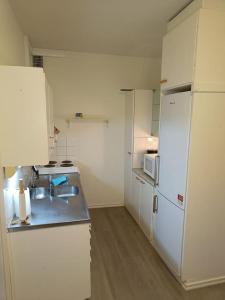 a white kitchen with a sink and a refrigerator at Huoneisto Kemin ydinkeskustassa in Kemi