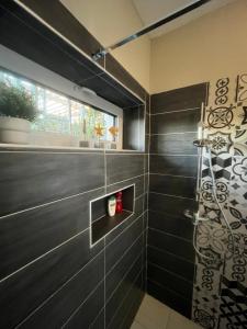 baño con ducha de azulejos negros en Zebikuckó en Zebegény