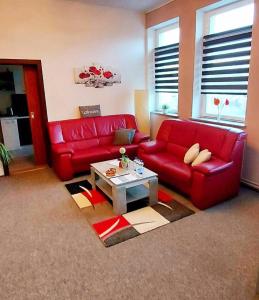 a living room with a red couch and a coffee table at Ferienwohnung "Blick Mylau" - Nähe Freizeitpark Plohn & Göltzschtalbrücke in Reichenbach im Vogtland