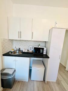 a small kitchen with white cabinets and a sink at Private Studio Flat in City 1190 in London