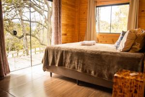 ein Schlafzimmer mit einem Bett und einem großen Fenster in der Unterkunft Cabana na Serra Catarinense in Bom Retiro