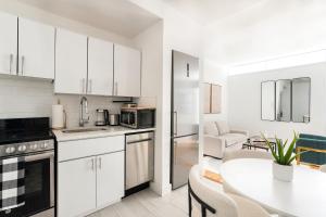 a kitchen with white cabinets and a table and a dining room at 444-2E Modern 2BR Hell's Kitchen in New York