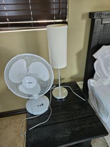 a table with a lamp and a fan on it at The Hide in Sandton 2 in Sandton