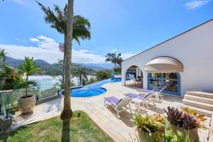 a villa with a swimming pool and palm trees at “Casa de alto padrão com ampla vista para o mar.” in Ubatuba