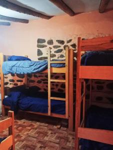a bedroom with three bunk beds in a room with a stone wall at Sacred Point in Ollantaytambo