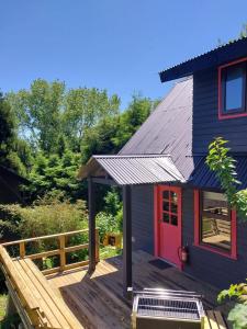 uma casa azul com uma porta vermelha num deque de madeira em CIPRES Ecolodge & Spa em Frutillar