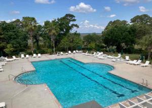 a swimming pool with white chairs and chairs and a pool at Habersham Retreat on Abbey Row in Beaufort