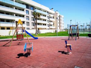 a playground with two swings and a slide at Los Alamos Beach - Parking in Torremolinos