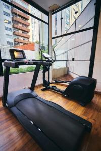 a gym with a treadmill in a room with windows at Quality Paulista (São Paulo, Jardins) in Sao Paulo