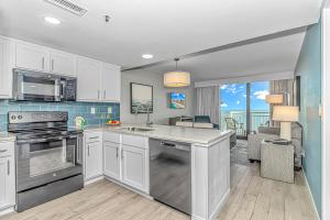 a kitchen with stainless steel appliances and a living room at Stunning Oceanfront 2 Bedroom Suite- Sailfish Resort 1111 in Myrtle Beach