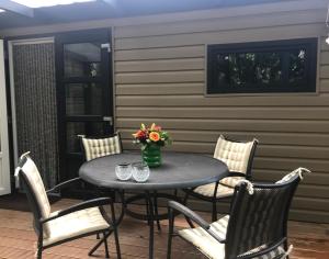 een terrastafel met stoelen en een vaas met bloemen bij De Tip 31 Tiny Chalet in Zeeland