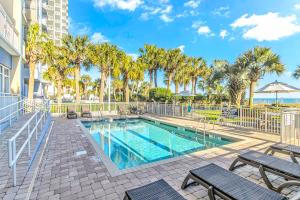 a swimming pool with chairs and palm trees at Stunning Oceanfront 2 Bedroom Suite- Sailfish Resort 1111 in Myrtle Beach