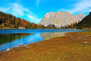 un reflejo de montaña en un lago con árboles y césped en Martins Apartmenthaus en Biberwier