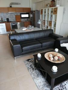 a black leather couch in a living room with a table at Sea and Sun Luxury apartment in Neoi Epivates
