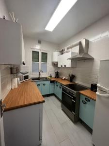a large kitchen with blue cabinets and a sink at Piso completo a 5 minutos del metro linea 5 verde in Madrid