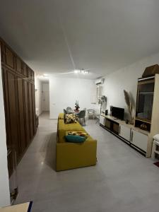 uma sala de estar com um sofá amarelo e uma televisão em Piso completo a 5 minutos del metro linea 5 verde em Madrid