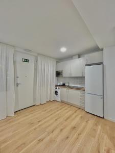 cocina con electrodomésticos blancos y suelo de madera en Lofts 4Towers - La Paz en Madrid