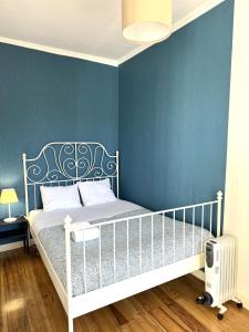リスボンにあるCasa dos Mastrosのベッドルーム1室(白いベッド1台、青い壁付)