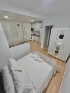 a white bedroom with a bed with towels on it at Lofts 4Towers - La Paz in Madrid