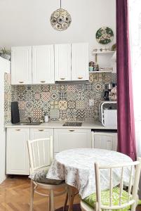 a kitchen with white cabinets and a table and chairs at Hestia Lux in Cluj-Napoca