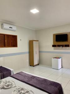 Martins的住宿－POUSADA NOVO HORIZONTE，客房设有两张床和一台墙上的电视。