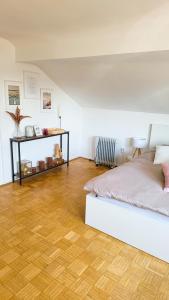 Schlafzimmer mit einem weißen Bett und Holzboden in der Unterkunft DG Links -Wunderschöne 40m² große City Wohnung nähe Salzburg in Freilassing