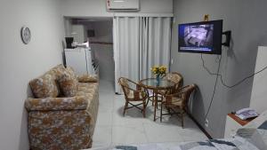 a living room with a table and chairs and a television at FLAT O POINT do CARNAVAL do FAROL da BARRA in Salvador